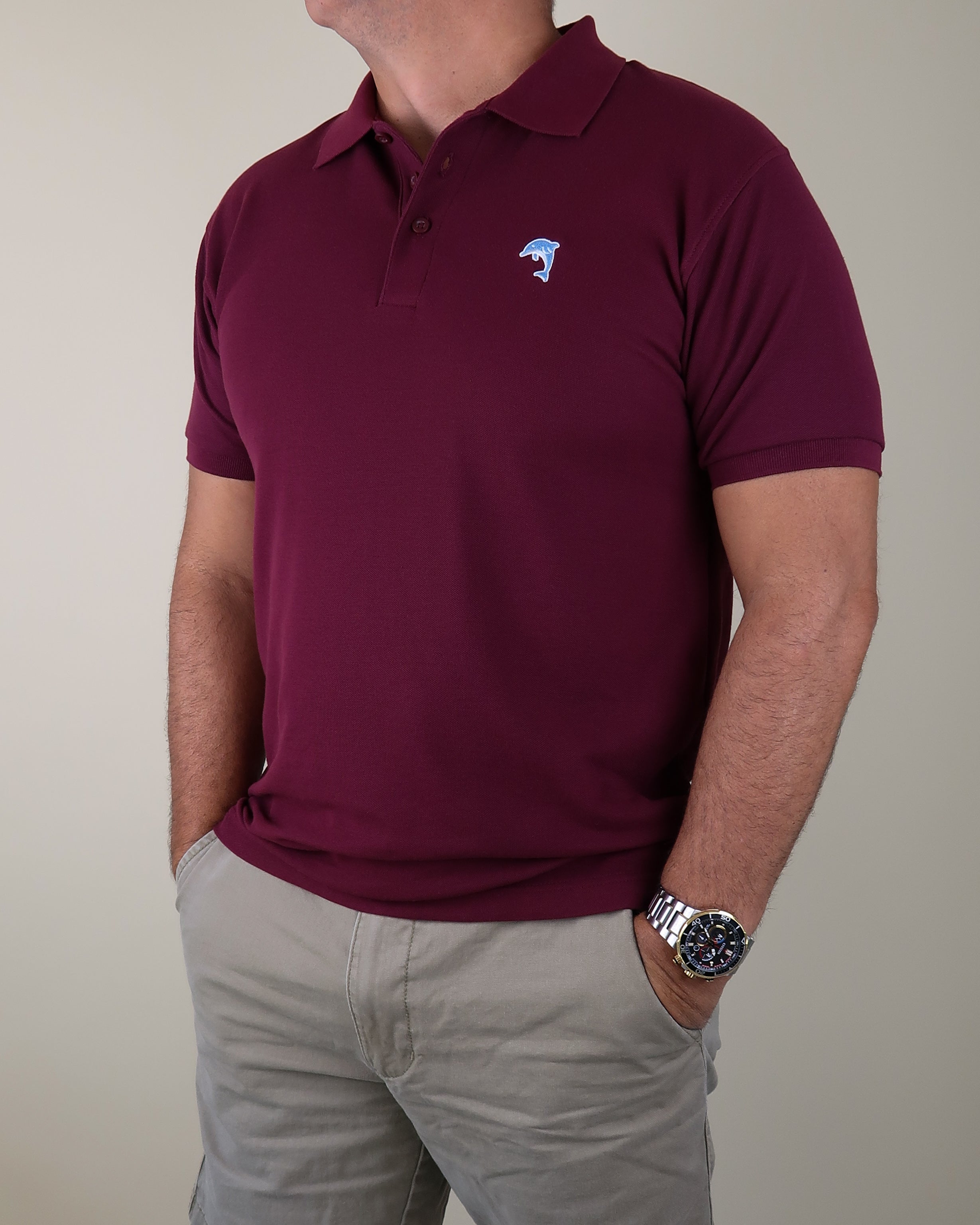 Maroon polo shirt with a dolphin logo worn by a person on a beige background