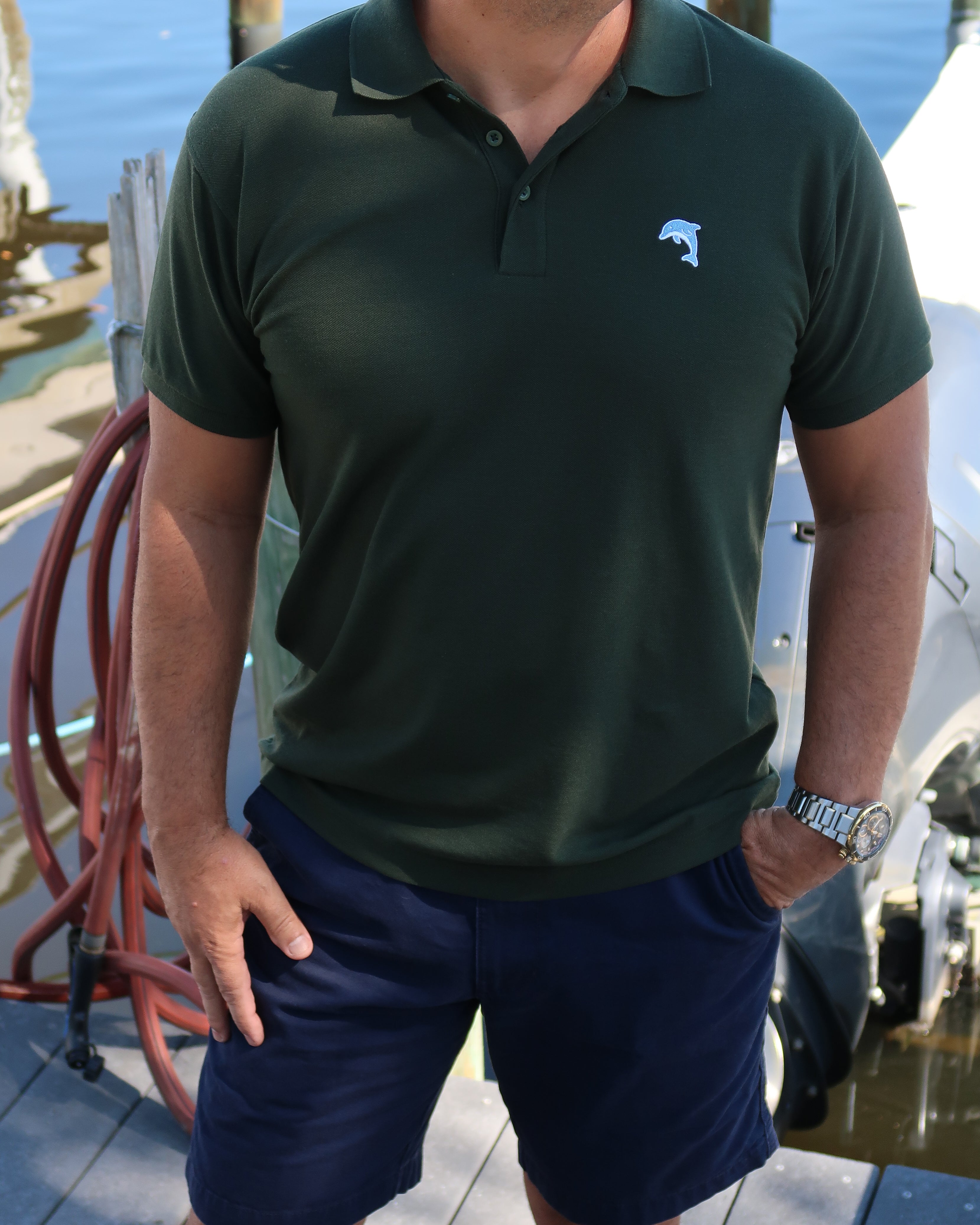 Person wearing a green polo shirt with a dolphin logo on a boat dock