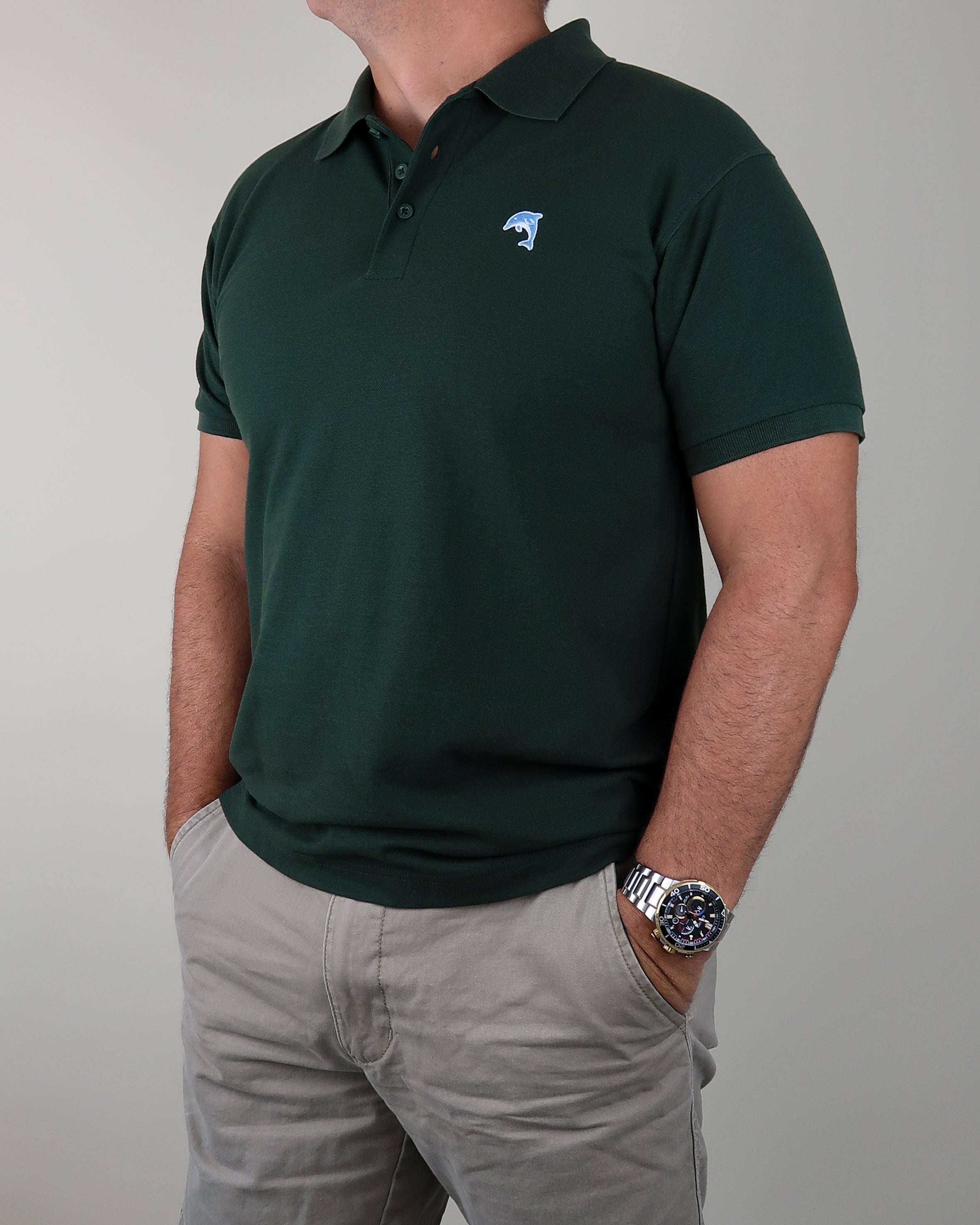 Person wearing a green polo shirt with a dolphin logo on a plain background
