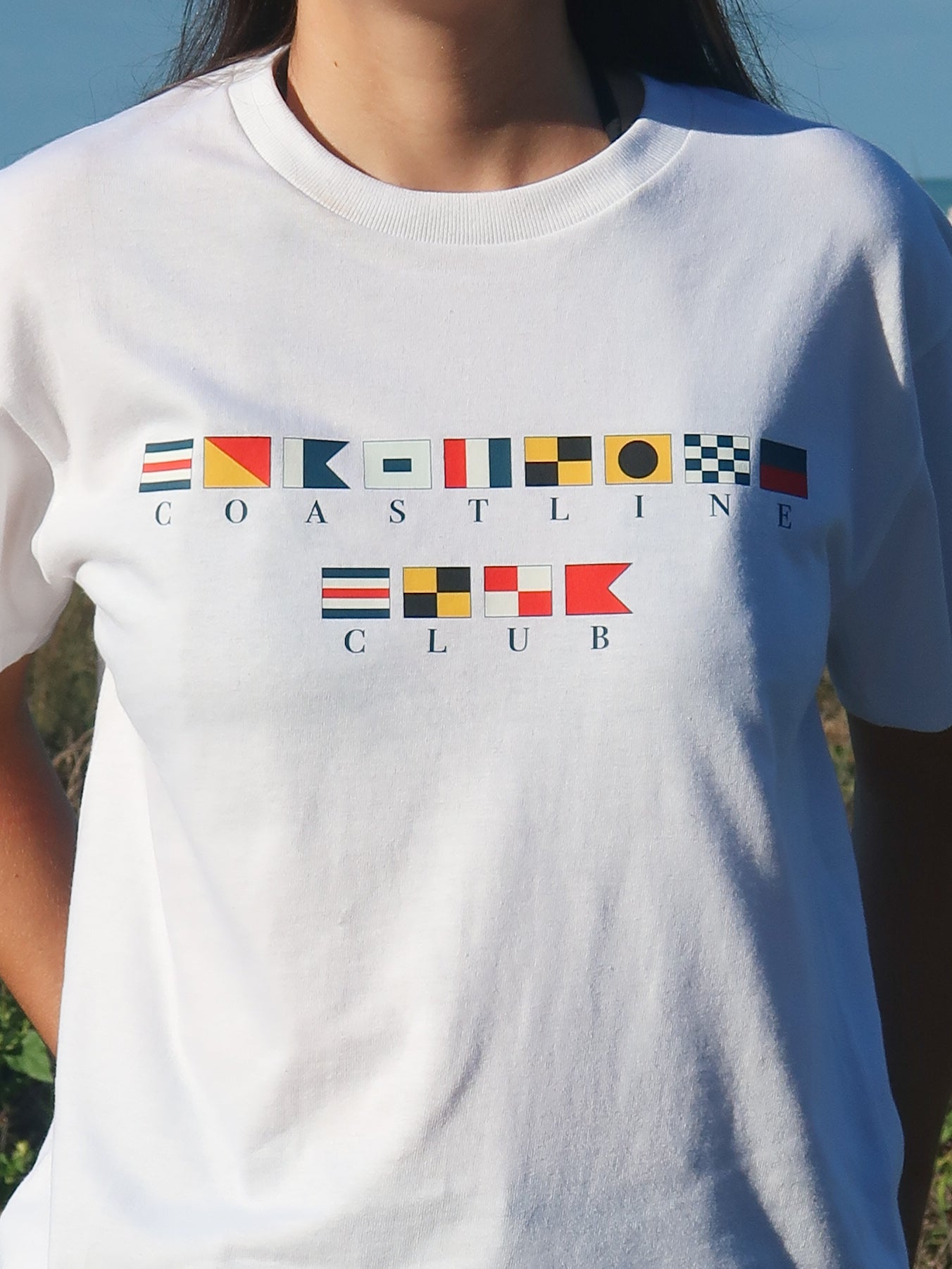 Close up of a white t-shirt with Maritime flags that spell out 'Coastline Club'