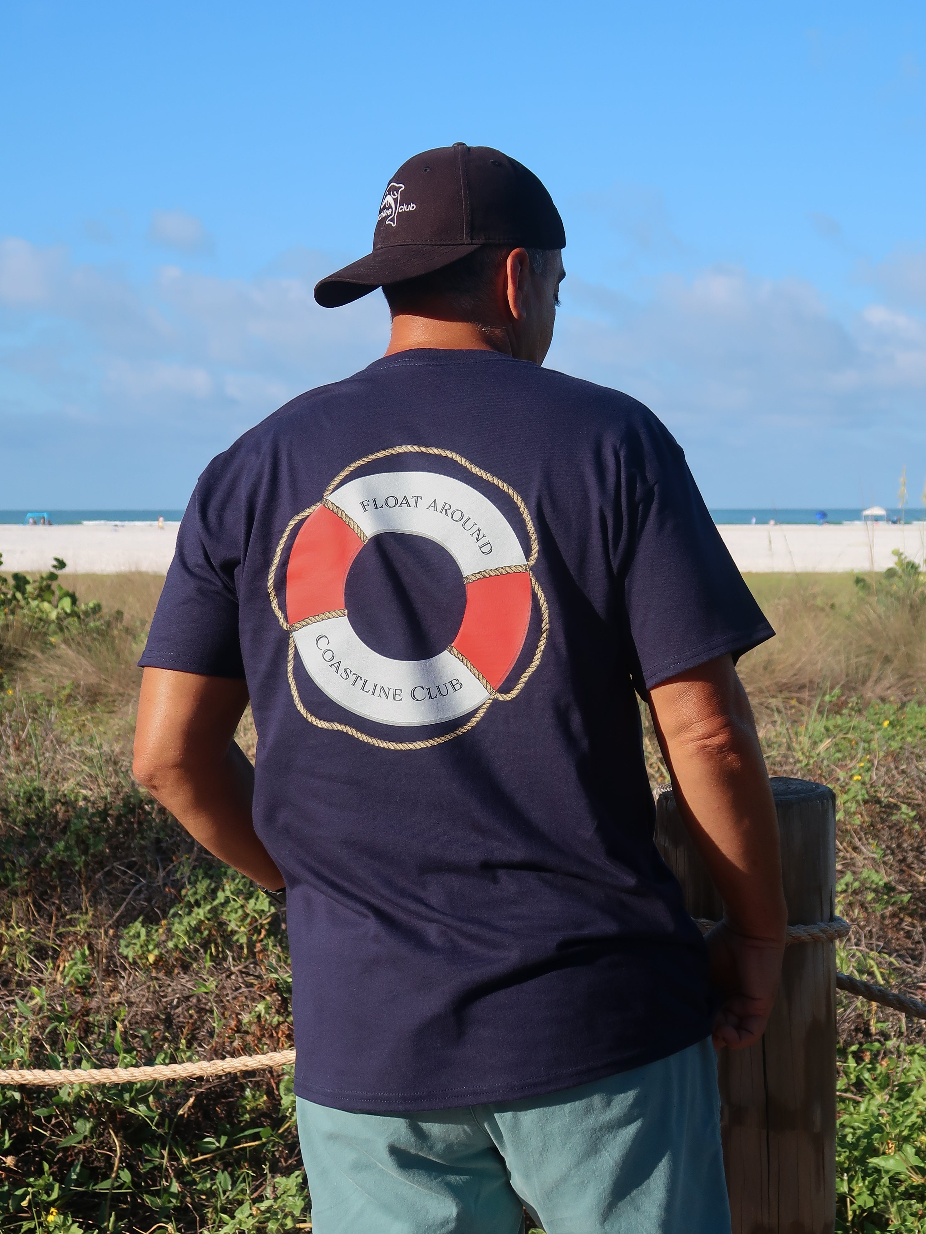 Man wearing a navy blue t-shirt with a life buoy graphic on the beach