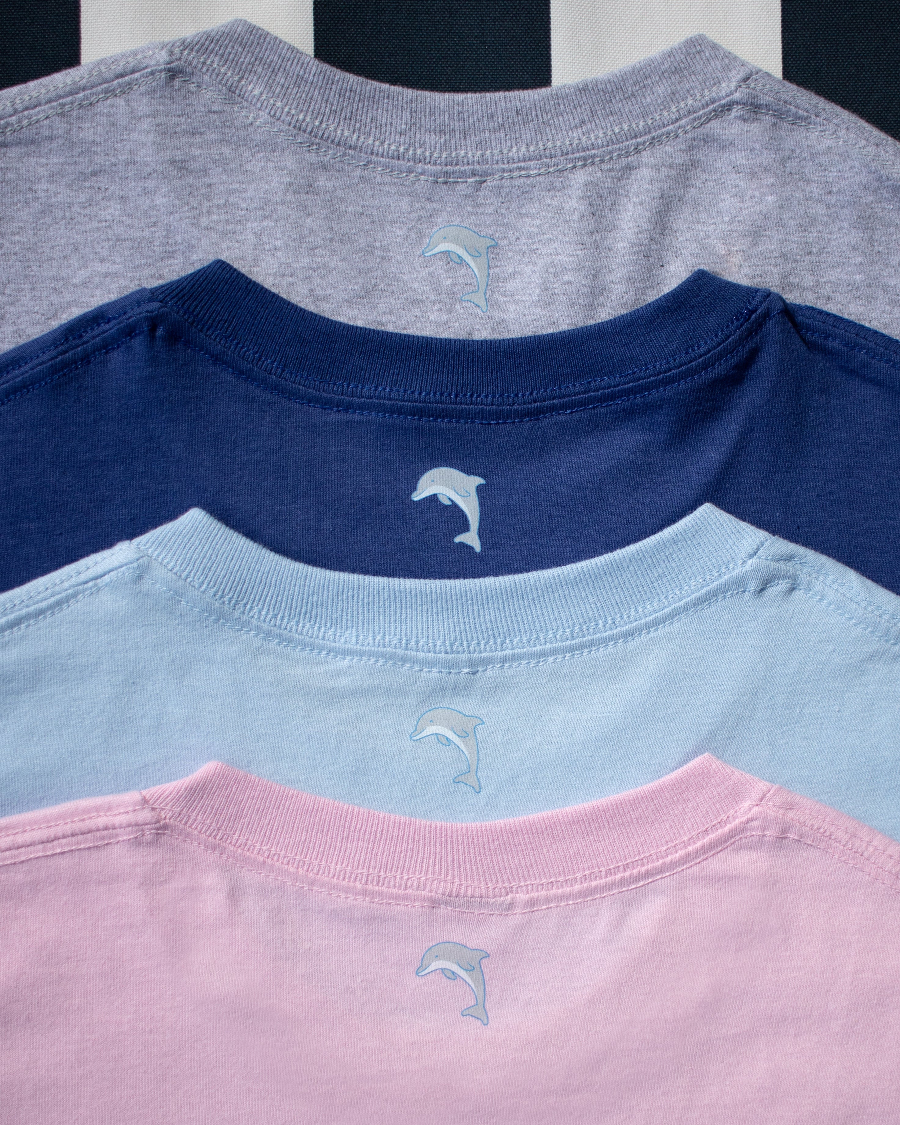 Four shirts in pink, blue, navy, and gray with a logo on a black and white striped background.