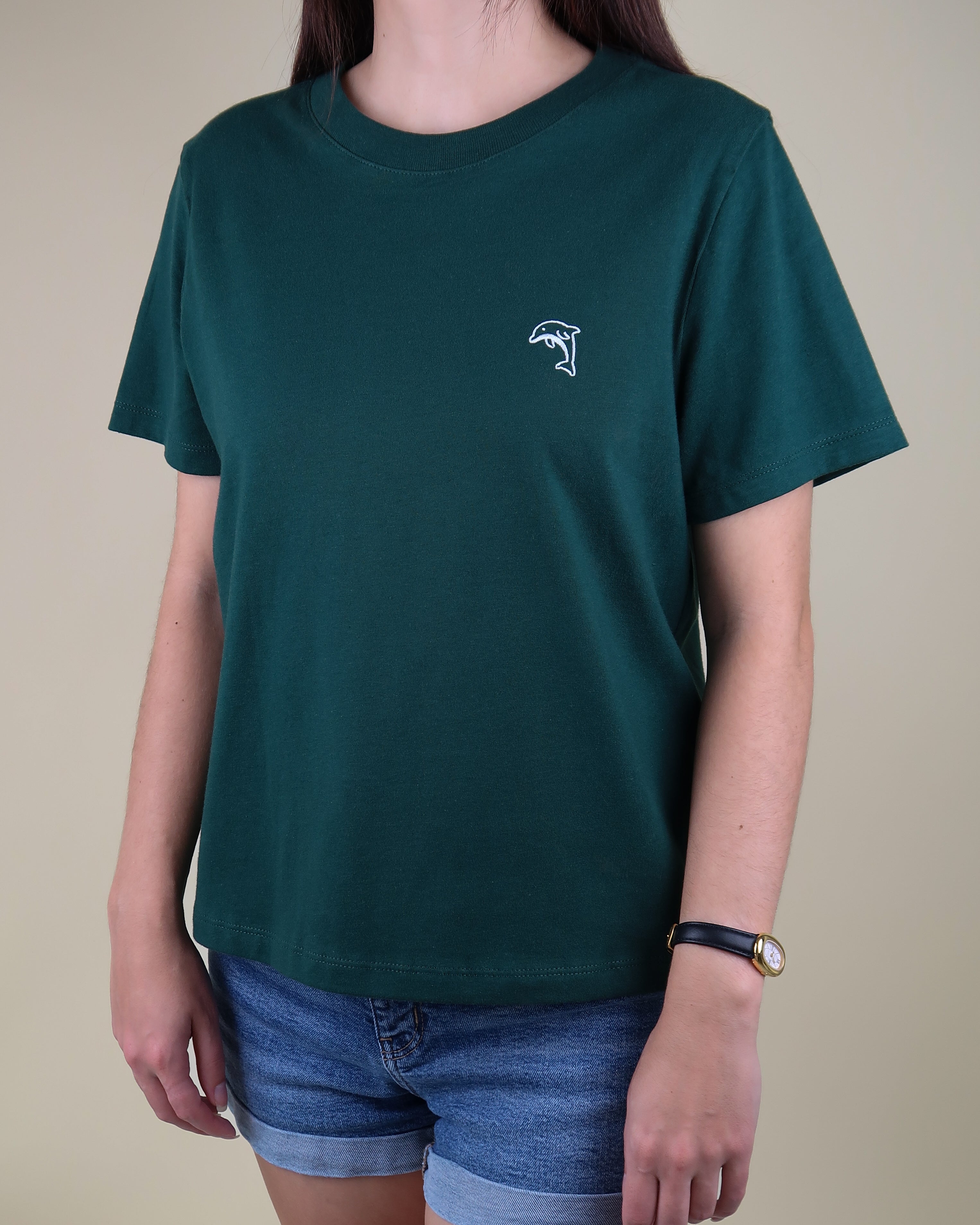 Person wearing a green t-shirt with a dolphin logo on a beige background