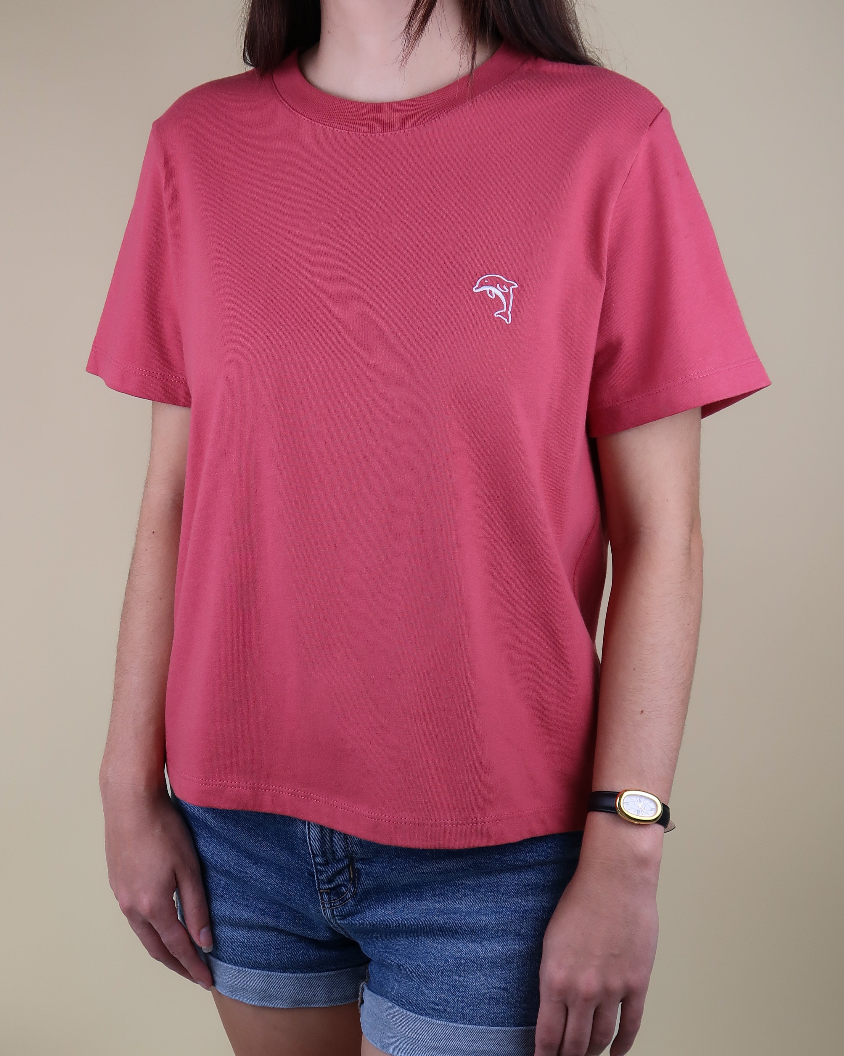 Person wearing a red t-shirt with a dolphin logo on a beige background