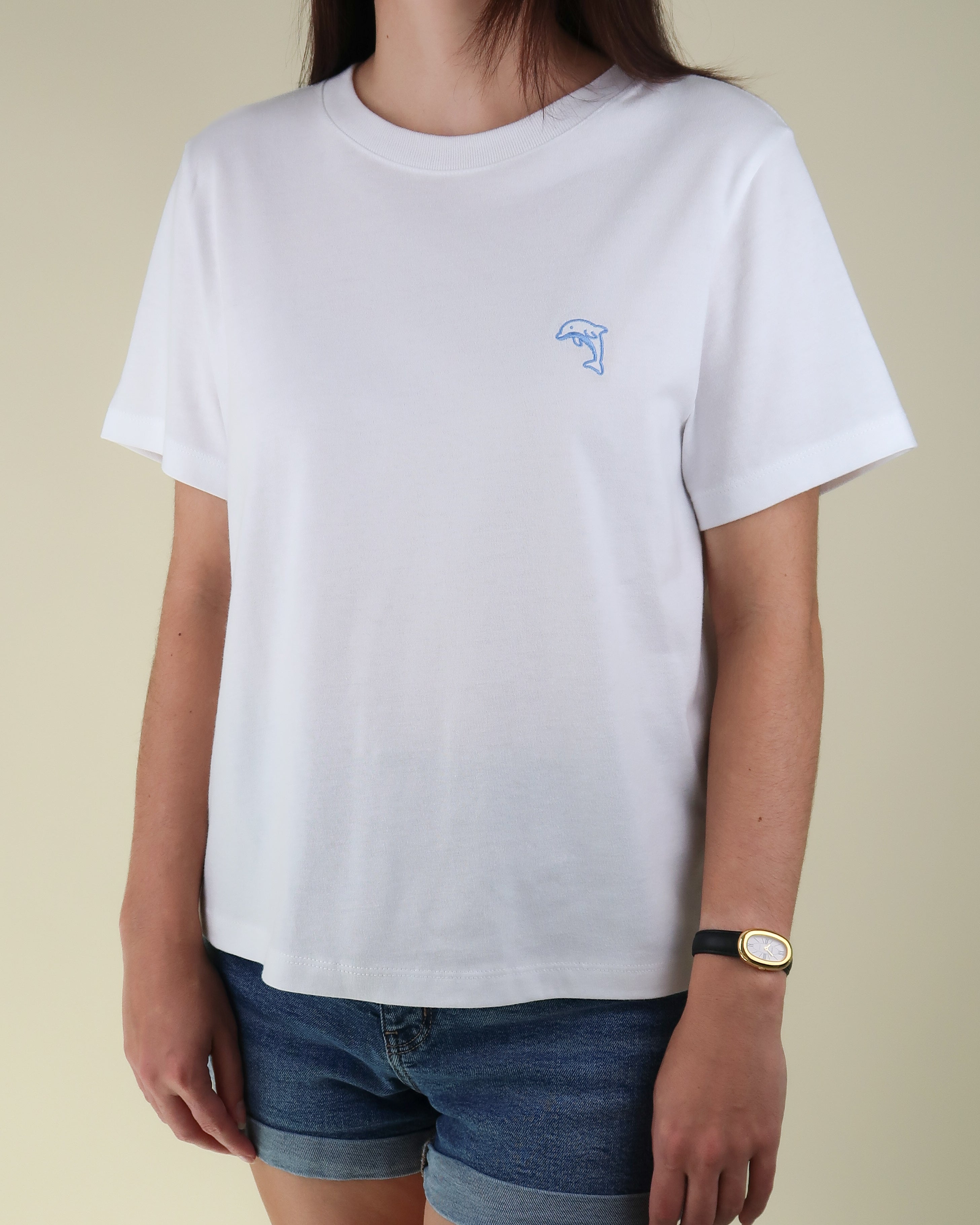 Person wearing a white t-shirt with a dolphin logo on a beige background